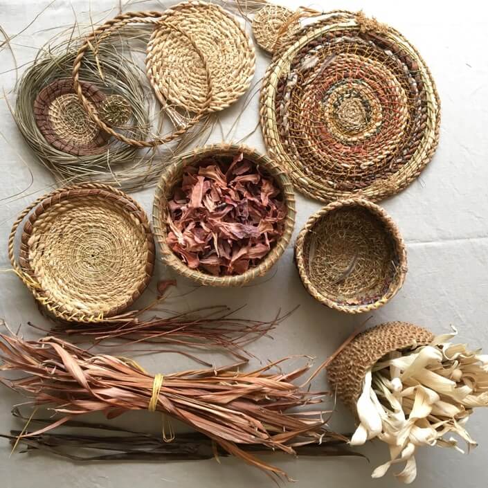 A basket filled with DIY garden craft supplies such as mosaic tiles, decorative stones, paint pens